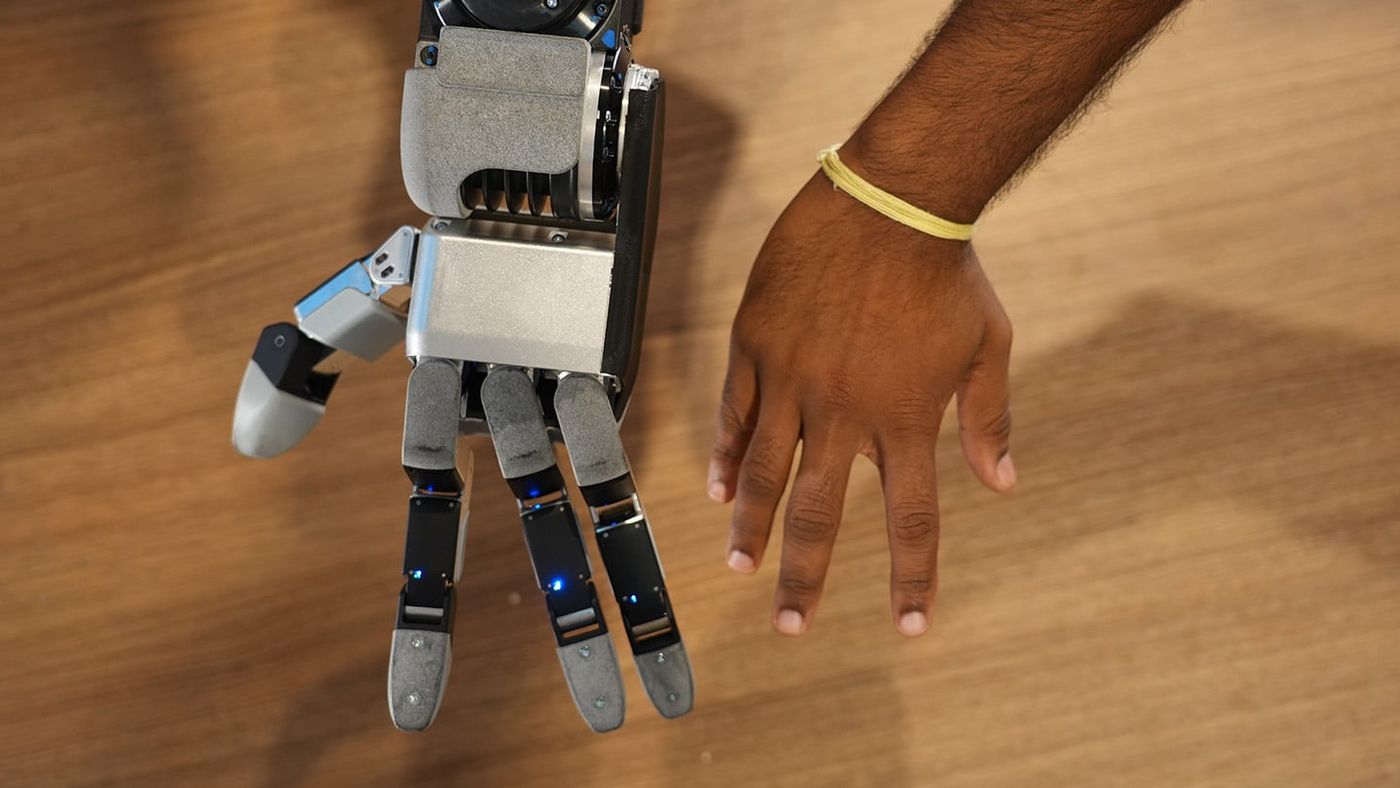 Boston Dynamics' new Atlas hand, with four fingers, lying next to a human hand